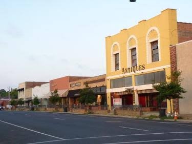 A row of historic storefronts in downtown Bastrop, including a yellow antiques building